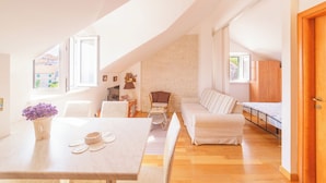 Uma sala de estar espaçosa com pé-alto, área de jantar e um canto aconchegante com sofá e mesa pequena.