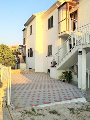 A building with a white facade, a staircase, and a patterned pavement.