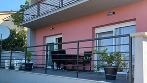 Un balcon avec une balustrade en métal, une table avec des chaises et des plantes en pot.