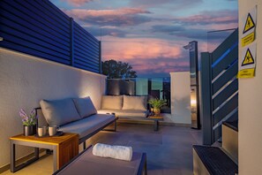 An outdoor seating area with a sofa, a small table, and a bench. There is a staircase to the right and a building entrance in the background. - Villa Vida (Vodice)