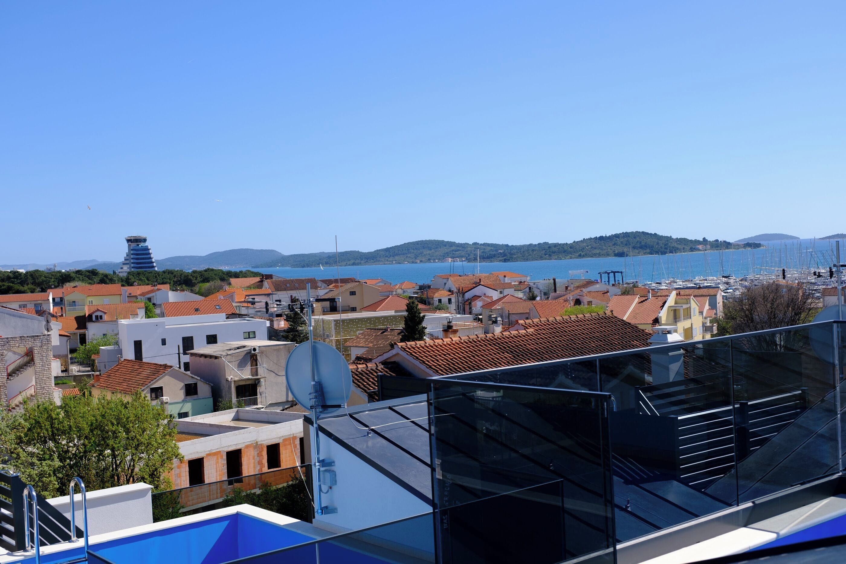 A coastal town with a clear view of the sea, a tower, and a mix of residential buildings.