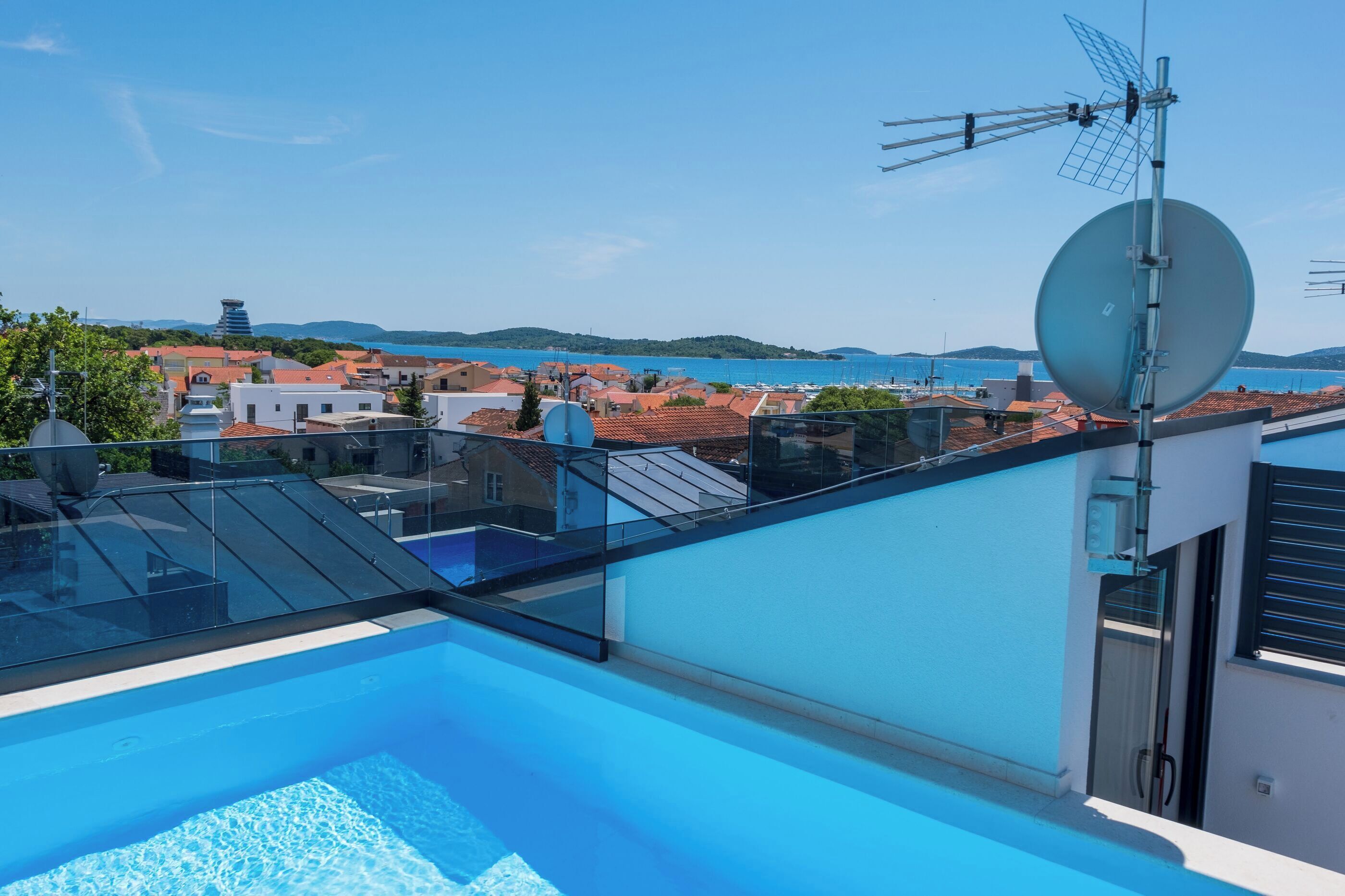 A rooftop pool with a clear view of the sea and buildings in the background.