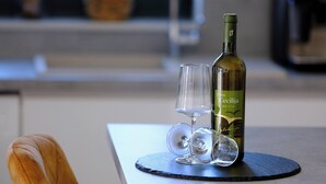 Ein Tisch mit einer Weinflasche, zwei Gläsern und einem Stuhl in einer modernen Küche.