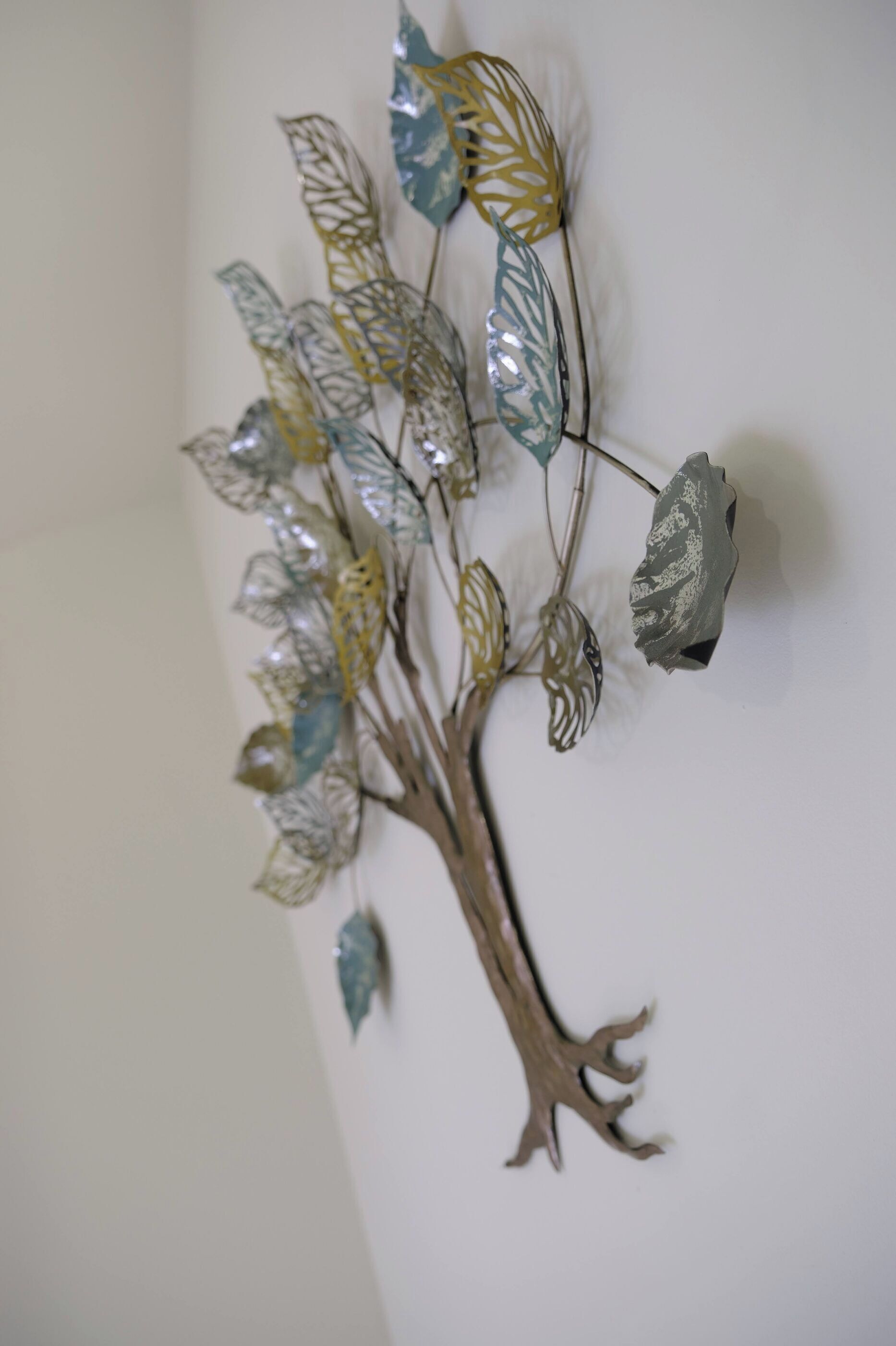 A wall-mounted decorative tree with metallic leaves and branches.