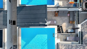 Ein Dachpool mit Glasgeländer, einer Liege und einer kleinen Sonnenterrasse mit Tisch und Stühlen.