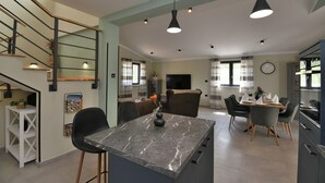 A modern kitchen with a marble countertop, black chairs, and pendant lighting. - Villa Vala (Marcana)