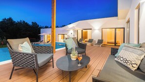 A modern outdoor living area with a pool, lounge chairs, and a table with a drink. - Villa Istria Green (Krsan)