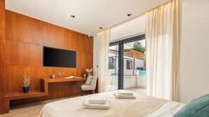 A modern hotel room with a large bed, a desk, a flat-screen TV, and a balcony with a view. - Villa Istria Green (Krsan)