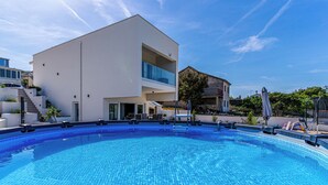 Ein modernes Gebäude mit Schwimmbad, Treppe und Balkon.