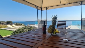 A wooden table with a glass of wine, a bottle, and a fruit bowl. - Villa Dream Come True (Jelsa)