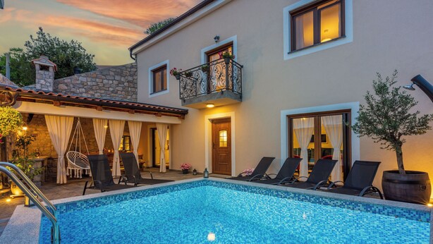 Une piscine avec des chaises longues et un mur en pierre.