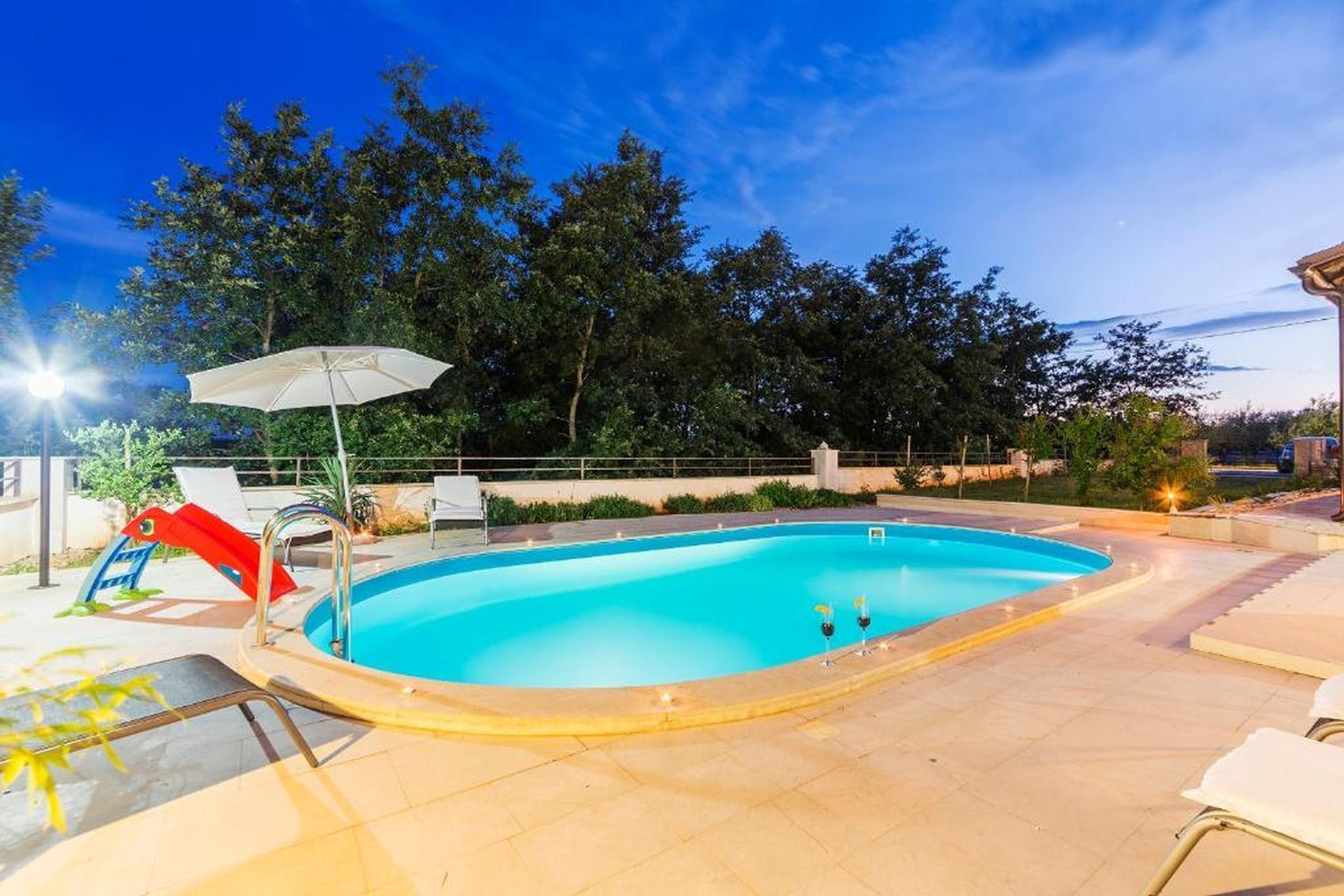 Ein Pool mit Rutsche, Liegestühlen und Sonnenschirm.