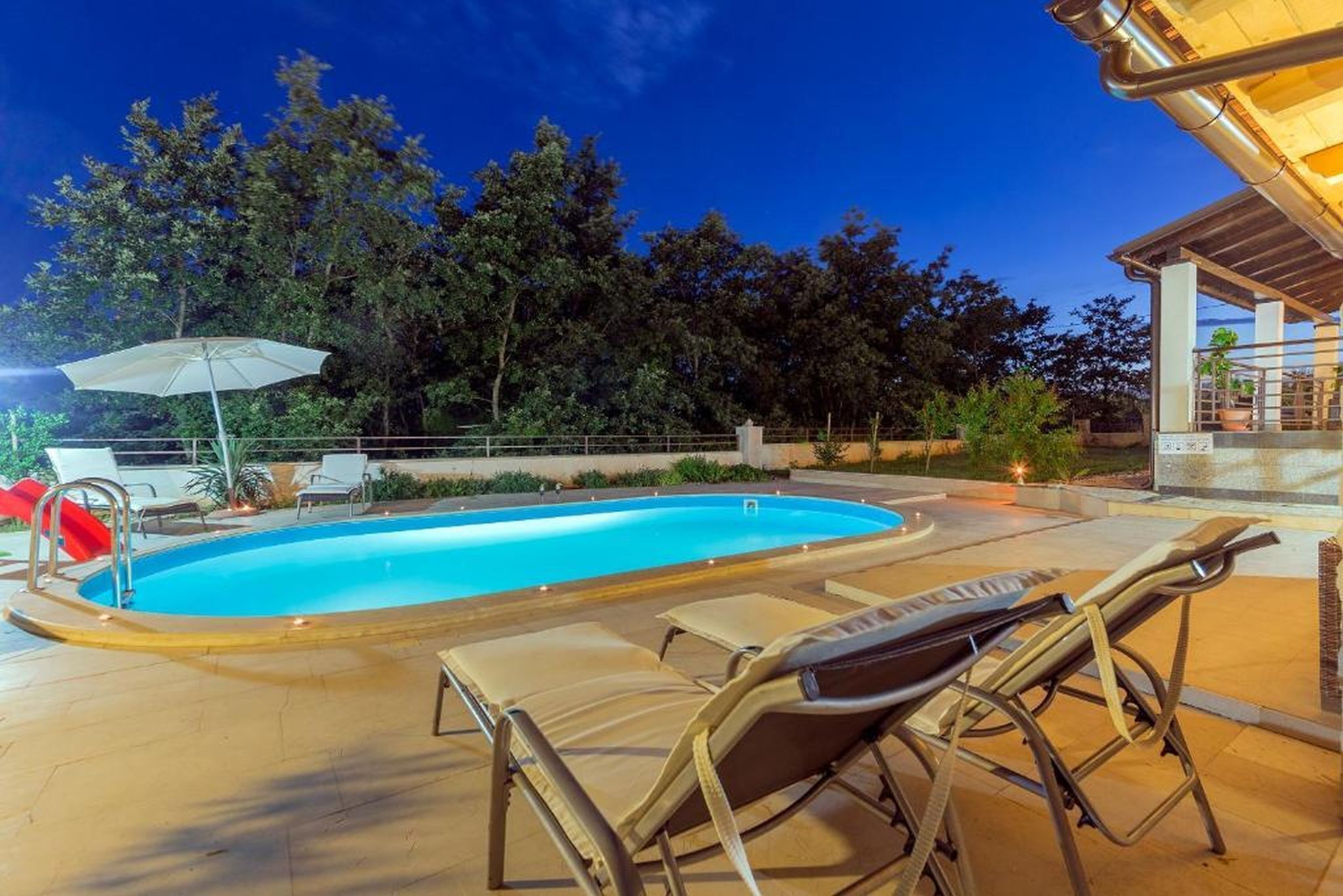 A swimming pool with lounge chairs and a covered area.