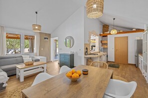 Uma sala de estar moderna com um sofá, uma mesa de jantar e uma tigela de frutas.