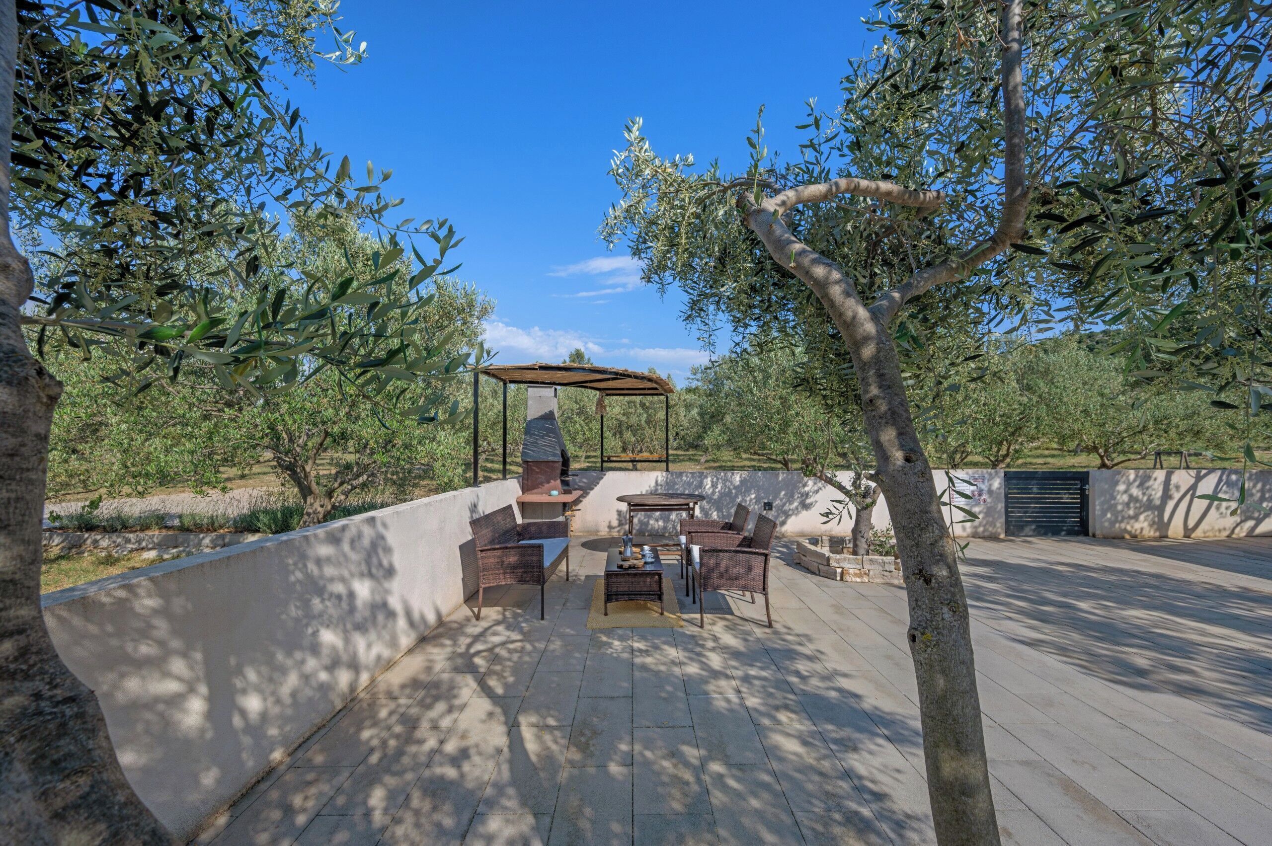 An outdoor patio with a barbecue area, seating, and a pergola.