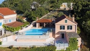 A hillside property with a swimming pool, a patio area, and a view of a hilltop building. - Villa Magnolia (Zadar)