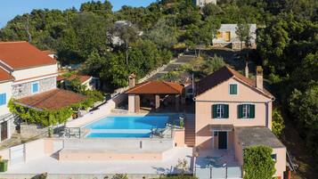 Propiedad en una ladera con piscina, un patio y vista a un edificio en la cima.