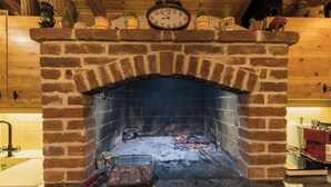 A brick fireplace with a clock above it, a glass container with meat, and a grill with charcoal below. - Villa Magnolia (Zadar)