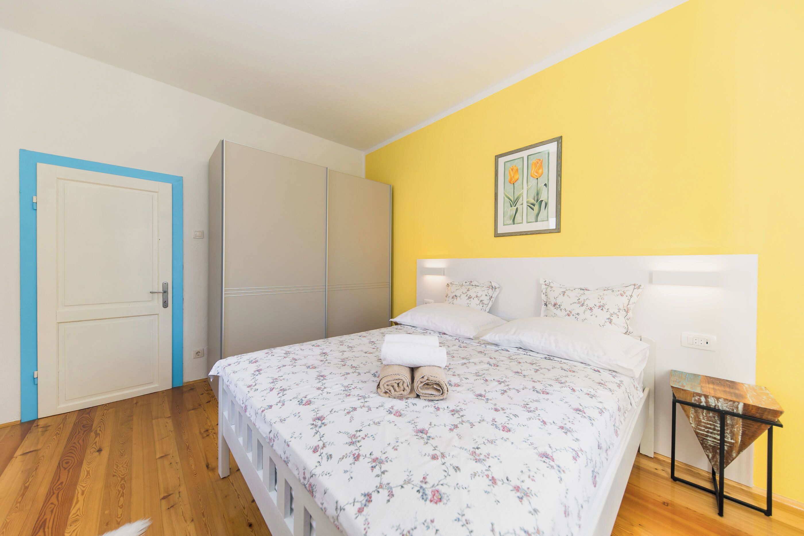 Un dormitorio con cama, armario, mesita de noche y puerta.