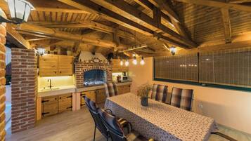 Una cocina rústica con vigas de madera a la vista, una chimenea de ladrillo y un comedor con mesa y sillas.