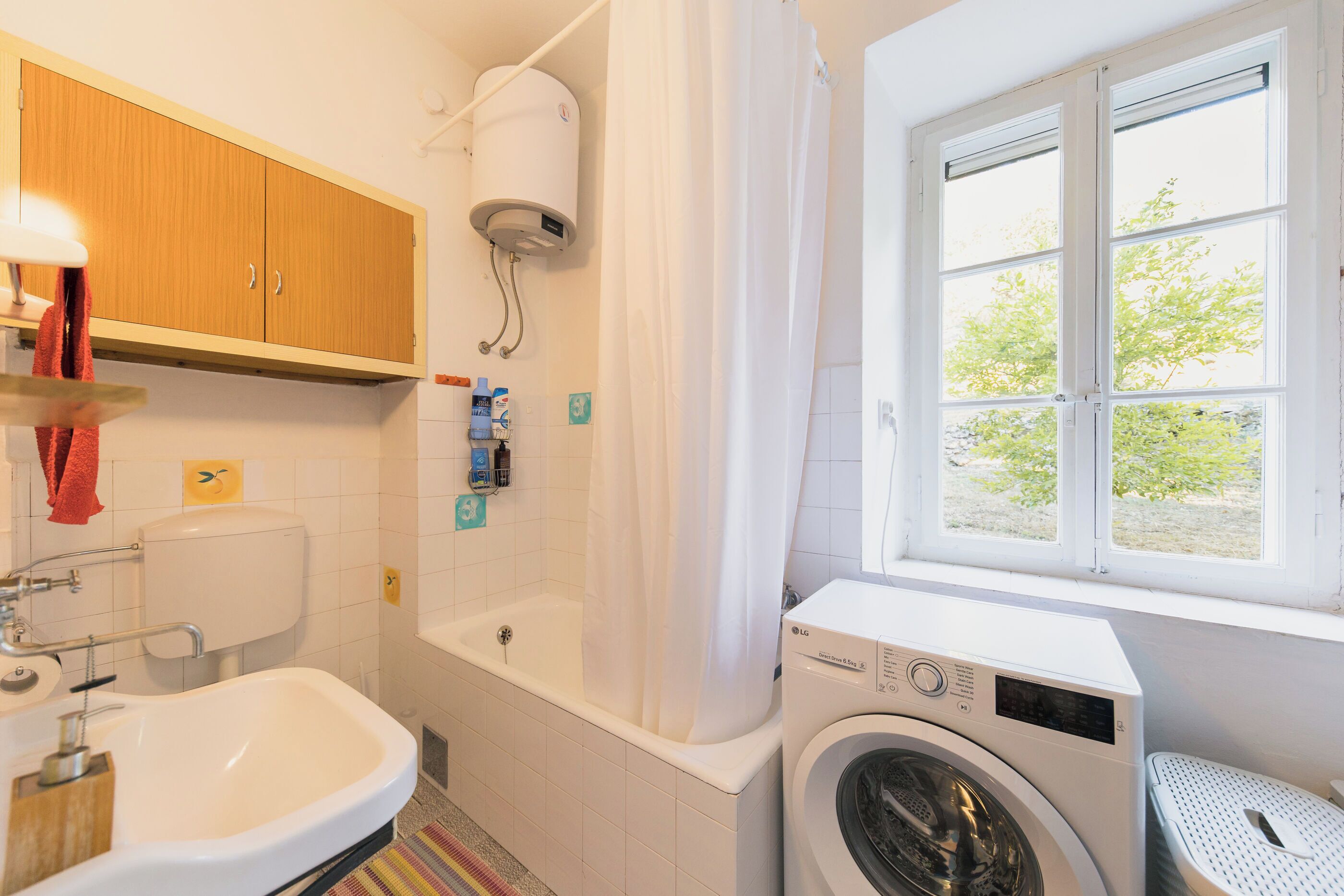 Une salle de bain équipée d’un lavabo, de toilettes, d’une baignoire et d’un lave-linge.
