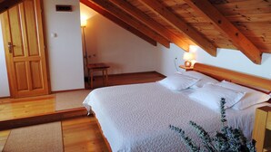 A bedroom with a wooden ceiling, a bed with white linens, a nightstand with a lamp, and a wooden door. - Villa Peace (Dugi Rat)