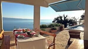 A table set for two with a view of the sea, a pool, and potted plants. - Villa Peace (Dugi Rat)