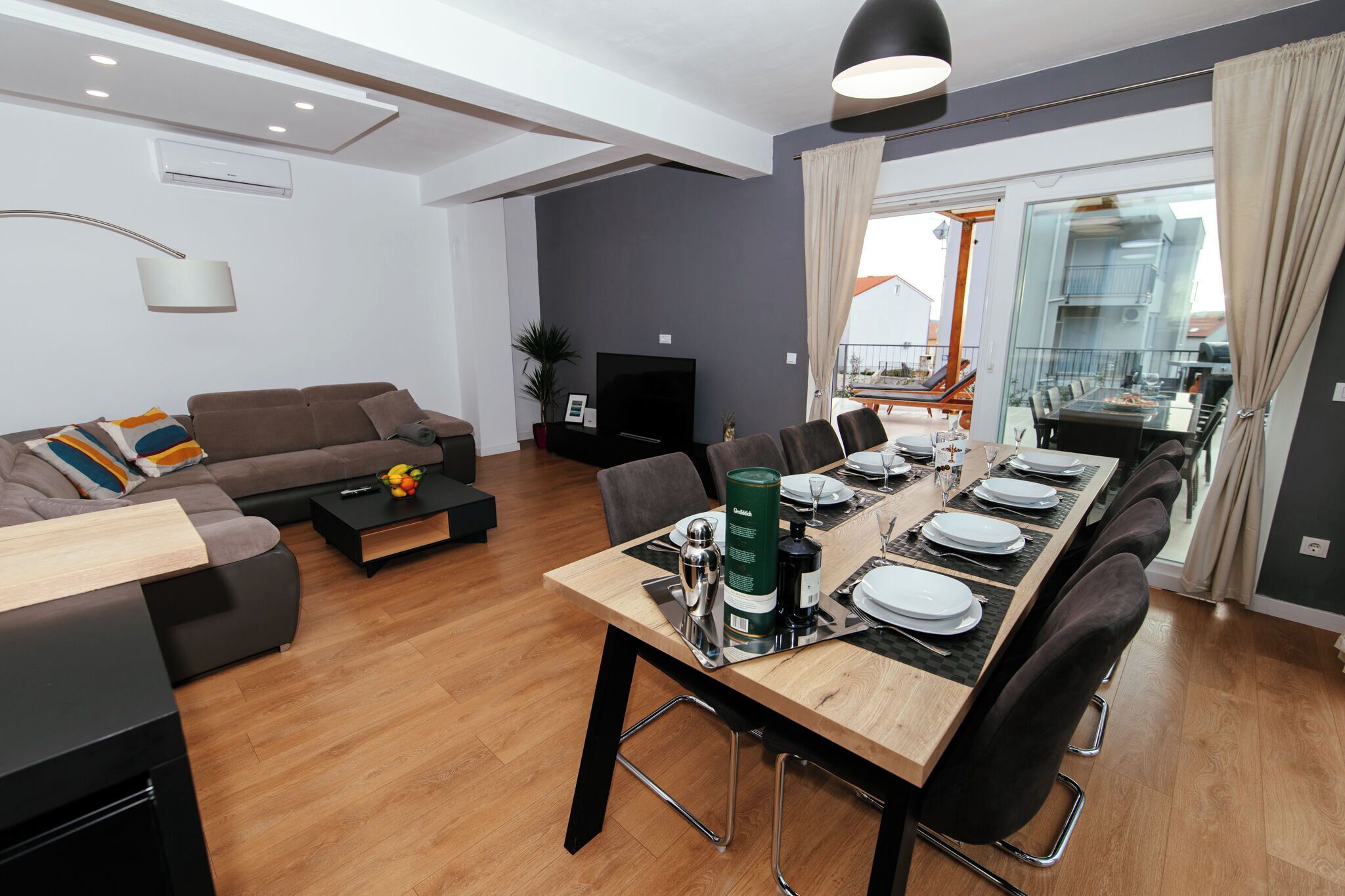 Un salon moderne comprenant un canapé, une table basse et un coin repas aménagé pour six personnes.