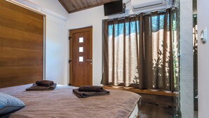Une chambre à coucher avec un lit, une porte en bois, une fenêtre avec des rideaux et un appareil de climatisation.