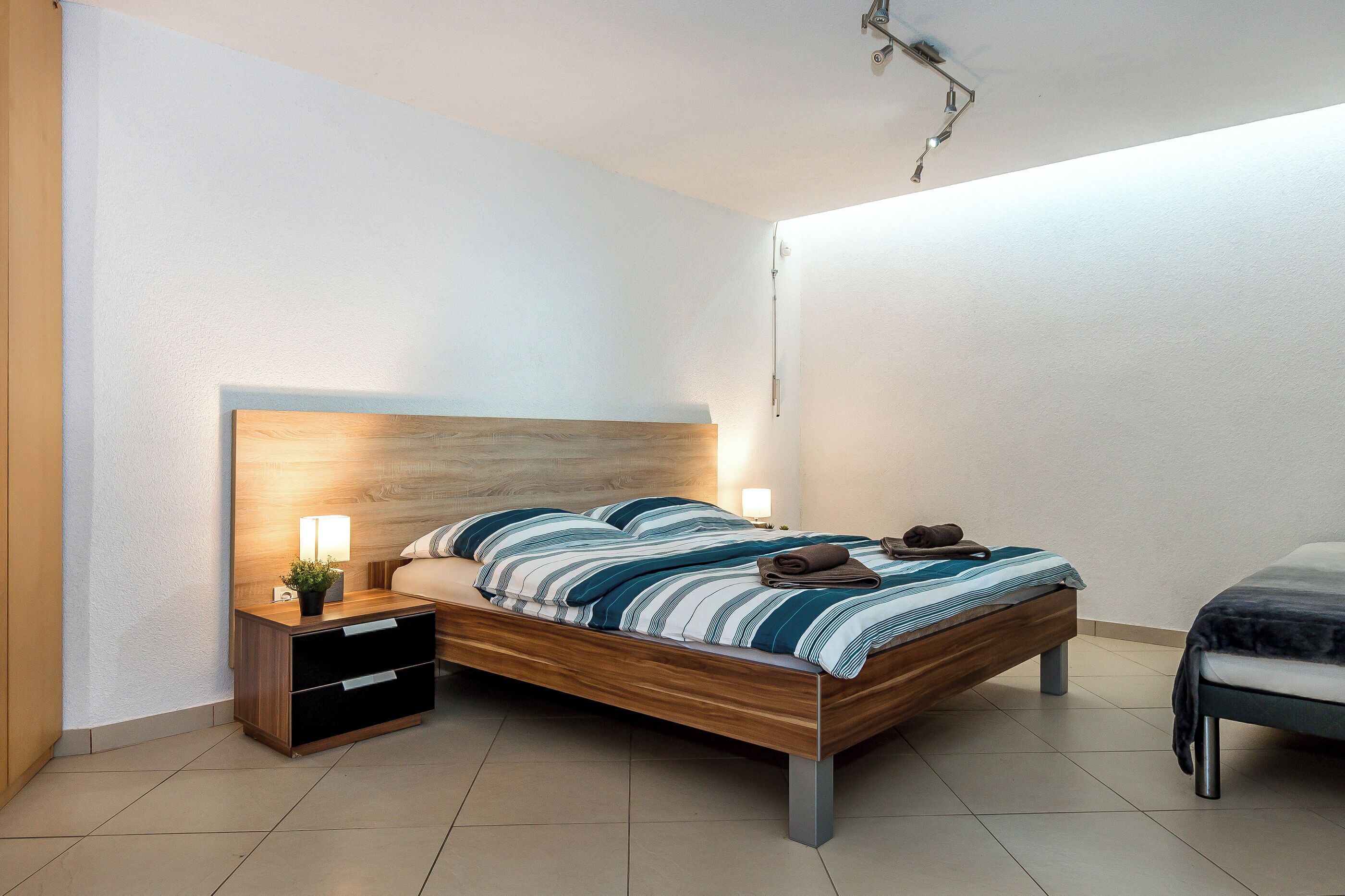 Une chambre à coucher moderne avec un lit en bois, des tables de chevet et une petite table de nuit.