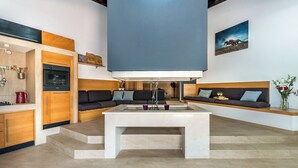 Un salon moderne doté d’une grande table centrale, d’un four encastré et d’un canapé avec des coussins.