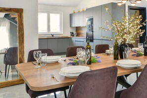 A dining area with a wooden table set for a meal, surrounded by chairs. - Villa Jolie (Privlaka)