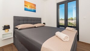 Un dormitorio moderno con una cama grande, una mesita de noche, una lámpara y un cuadro de una puesta de sol.