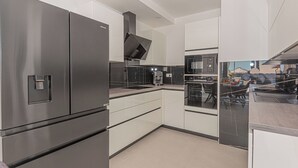 Una cocina moderna con electrodomésticos de acero inoxidable, armarios blancos y encimera negra.