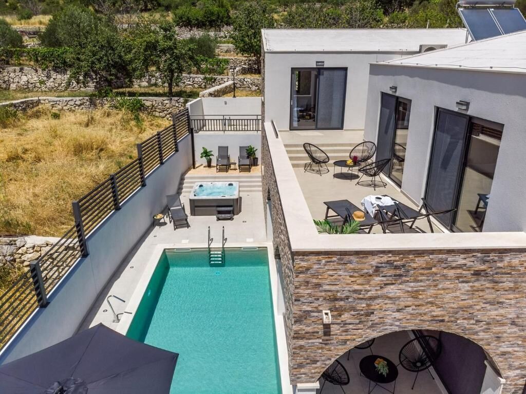 Une villa moderne dotée d’une piscine, d’un espace extérieur aménagé et d’un mur en pierre.