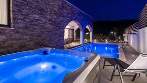 A swimming pool area with a stone wall, a hot tub, and lounge chairs. - Villa Eden With Heated Pool (Omis)