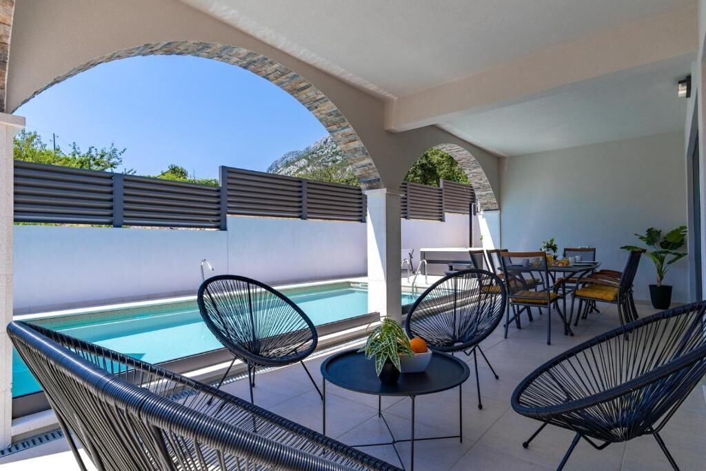 Un espace extérieur abrité comprenant une piscine, des chaises longues et une table avec des chaises.