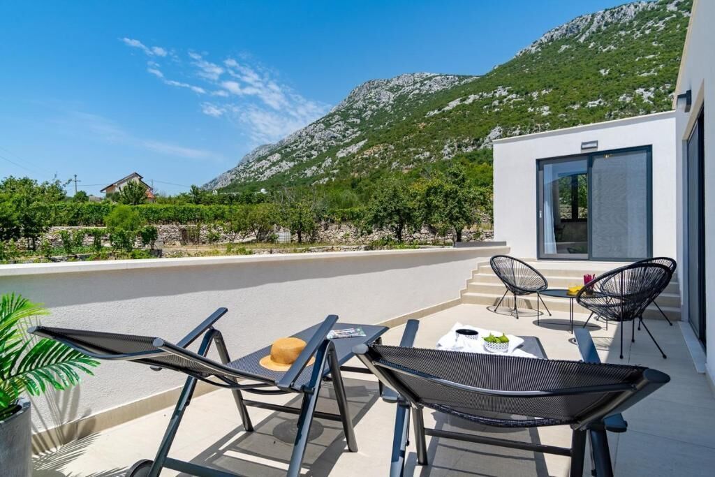 Un espace extérieur moderne aménagé avec une table, des chaises et un chapeau posé sur la table.
