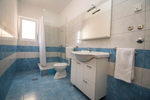 A bathroom with a shower, toilet, sink, and towel rack. - Apartments Marina View (Tribunj)