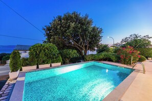 A rectangular swimming pool with a tiled edge, surrounded by greenery and a paved walkway. - Villa Roko (Novi Vinodolski)