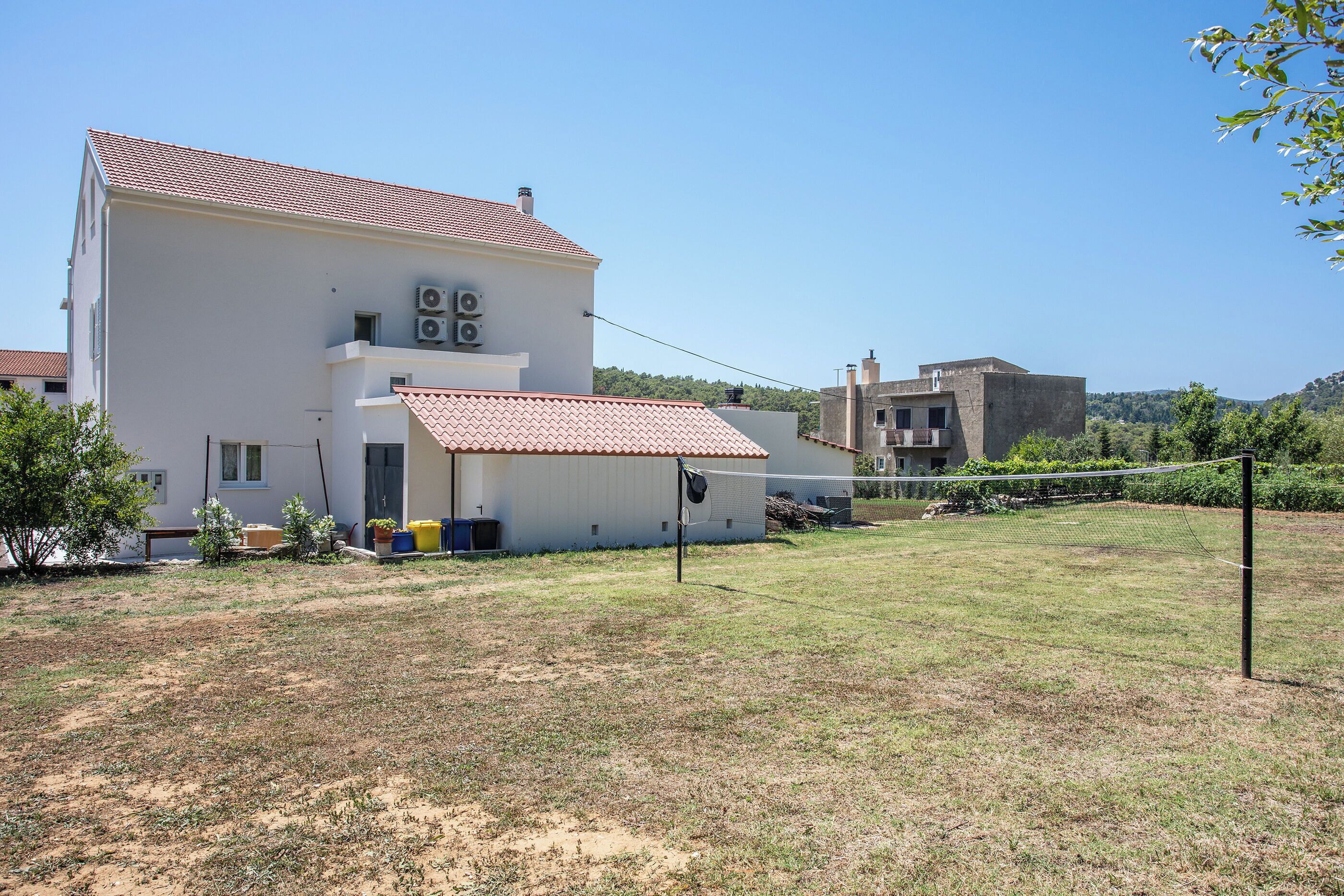A two-story building with a red-tiled roof, a flat facade, and a visible air conditioning unit.