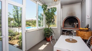 Um pátio com mesa, cadeiras, um vaso de planta e um forno de tijolos.