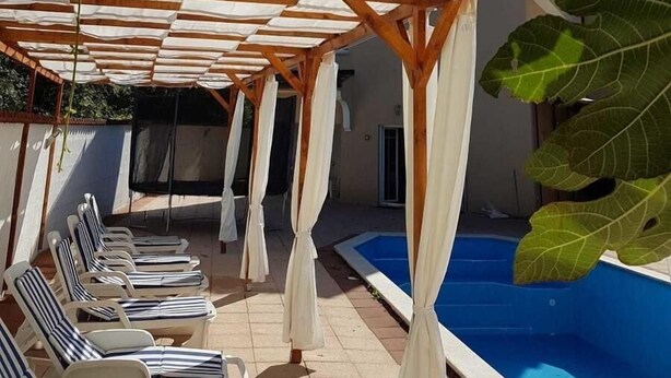 A covered outdoor area with a pool, lounge chairs, and a pergola structure. - Villa Spacious (Zminj)