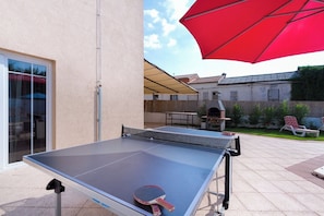 An outdoor ping pong table with a net, a red umbrella, and a barbecue grill in the background. - Villa Spacious (Zminj)
