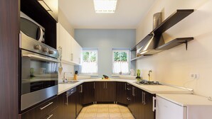 A modern kitchen with dark wood cabinets, stainless steel appliances, and a white countertop. - Villa Spacious (Zminj)