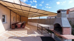 An outdoor patio with a checkered floor, a stone barbecue oven, and a covered seating area. - Villa Spacious (Zminj)