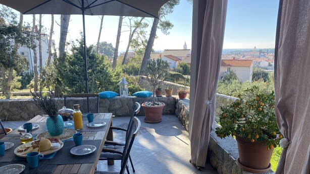 An outdoor patio with a table set for breakfast, surrounded by potted plants and a stone wall. - Villa Arba (Rab)