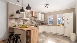 A modern kitchen with a wooden island, pendant lights, and a stone backsplash. - Villa Arba (Rab)
