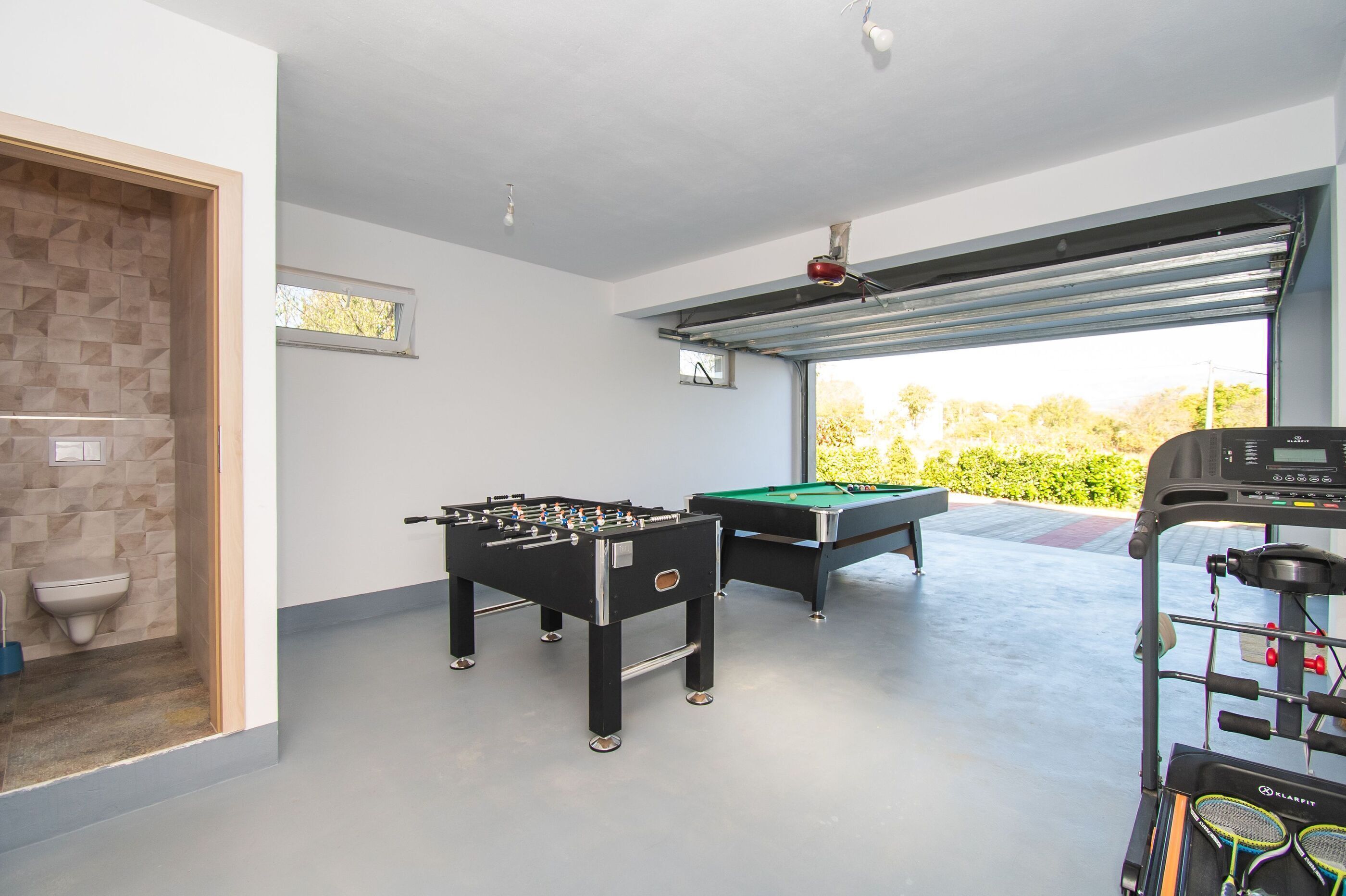 Una habitación con mesa de fútbol, mesa de billar y caminadora.