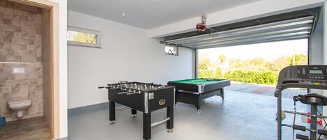 Una habitación con mesa de fútbol, mesa de billar y caminadora.